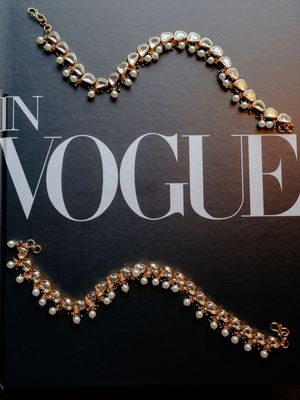 Elegant gold and pearl jewelry pieces displayed against a dark background with Vogue magazine text.