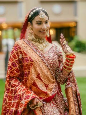 Close-up details of an ornate red and gold Indian bridal lehenga with intricate embroidery.