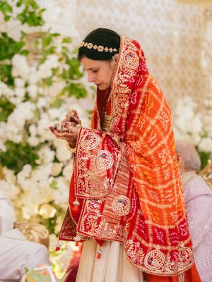 Traditional Indian wedding ceremony with bride in red and gold attire performing rituals.