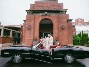 A vintage black convertible car parked in front of a brick building entrance with classic architecture.