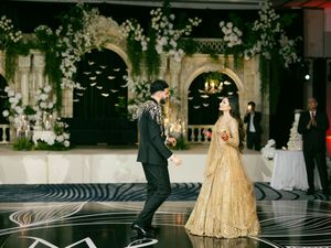 Elegant couples dancing at a formal ballroom event with swirling patterns on the floor and ornate architecture.