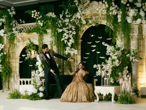 A romantic outdoor wedding ceremony setup with white floral arches and decorative lighting in an elegant garden setting.