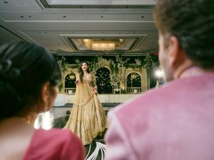 A model walks down a runway wearing a flowing gold gown at a fashion show.