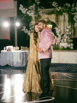 Couple shares a romantic dance on an elegant black and white patterned dance floor at an upscale wedding reception.