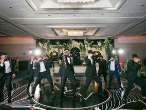 Wedding guests dance and celebrate on an elegant black and white patterned dance floor at an indoor reception.