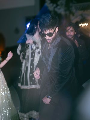 Wedding guests dance and celebrate on a dimly lit dance floor during an evening reception party.