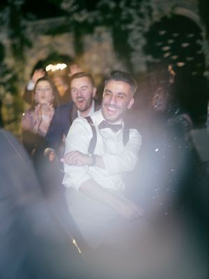 Wedding reception guests laugh and celebrate while enjoying the festivities in a dimly lit ballroom setting.