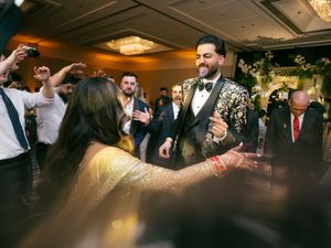 Guests celebrating on the dance floor with dramatic orange lighting at an indoor wedding reception.