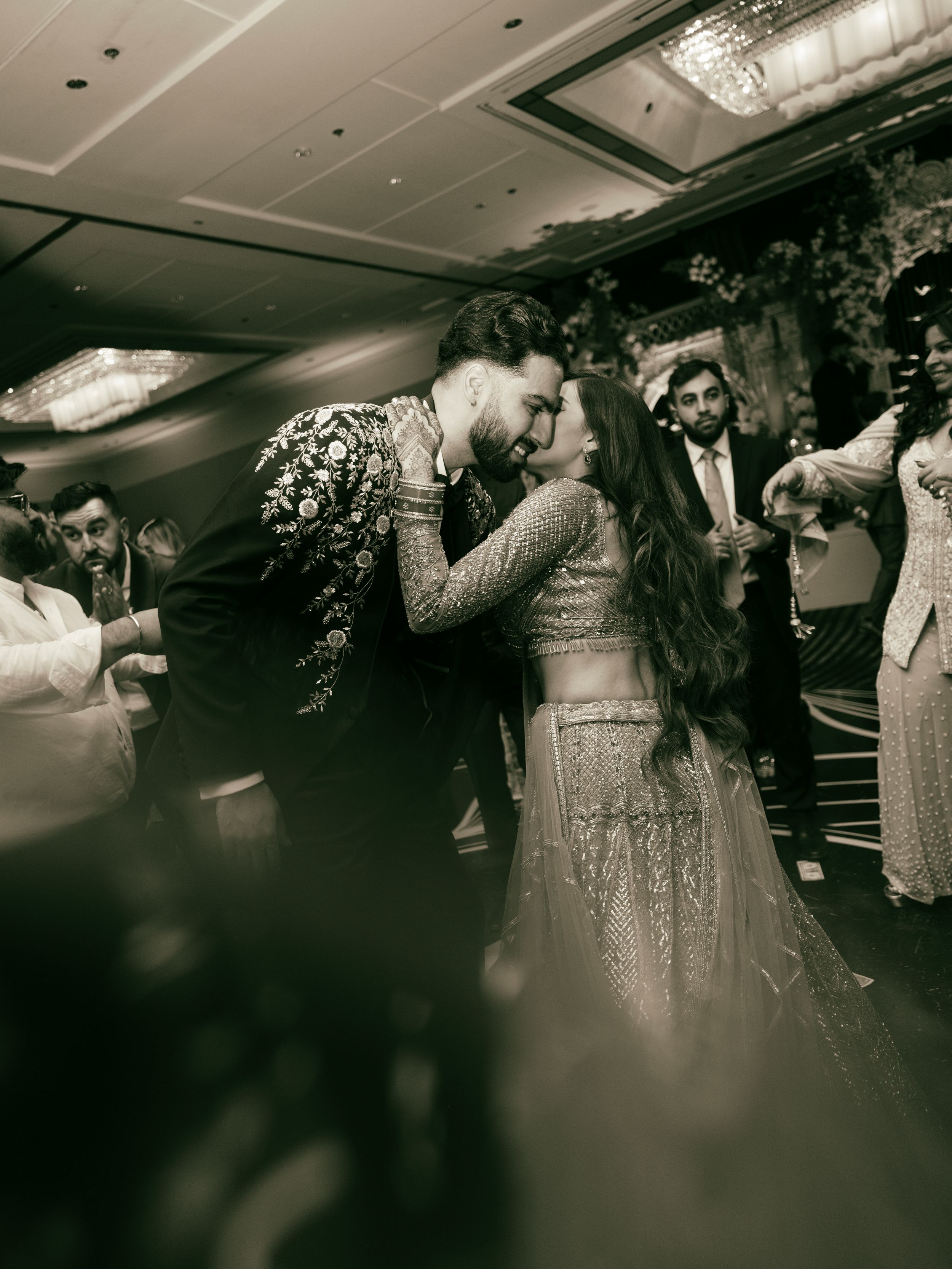 Wedding guests dancing in formal attire on a black and white dance floor captured in monochrome.