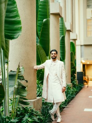 A couple poses in a tropical garden walkway with lush banana plants and white columns.