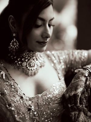 A dramatic black and white fashion portrait shows an ornate beaded neckpiece with intricate details in vintage style.