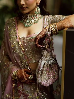 Ornate bridal attire featuring intricate embroidery, jewels, and delicate details in mauve and gold tones.