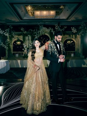 Elegant wedding reception venue with gold decor and dramatic lighting showcasing ornate table settings and dance floor.