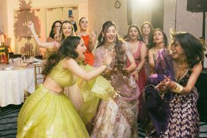 A festive celebration with people in colorful formal attire dancing and enjoying themselves at an indoor event.