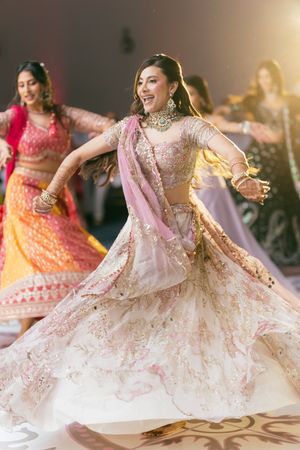 Bride in traditional Indian lehenga twirls gracefully during a wedding celebration, showcasing intricate embroidery details.