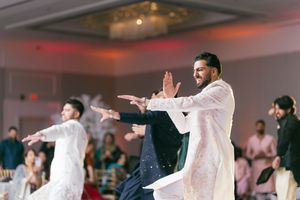 Wedding guests dance and celebrate on a ballroom floor with festive lighting and decorations.