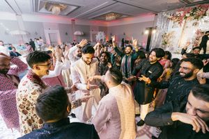 A lively crowd dances and celebrates at an indoor party with colorful lighting and decorative elements.