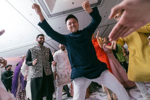 People dancing energetically at an indoor celebration with bright lighting and festive atmosphere.