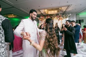 Wedding guests dance and celebrate on a brightly lit dance floor with green lighting at a reception venue.