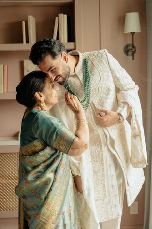 A sequence of tender moments between two people in traditional South Asian attire with a white wedding dress displayed.