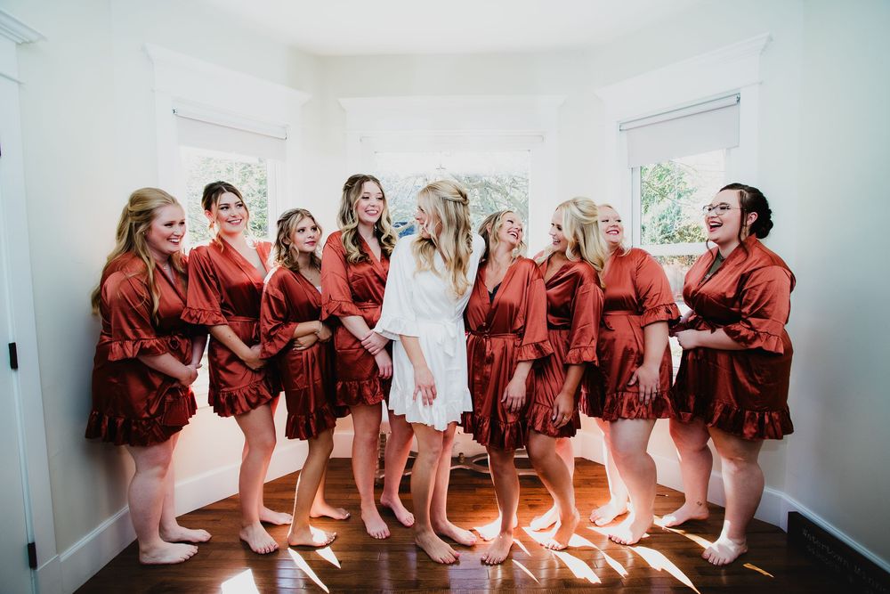 Group wearing matching red robes sitting in a row in a bright sunlit room.