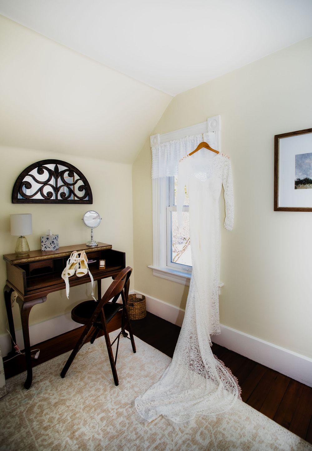 Elegant wedding dress hanging in a vintage-styled getting ready room.