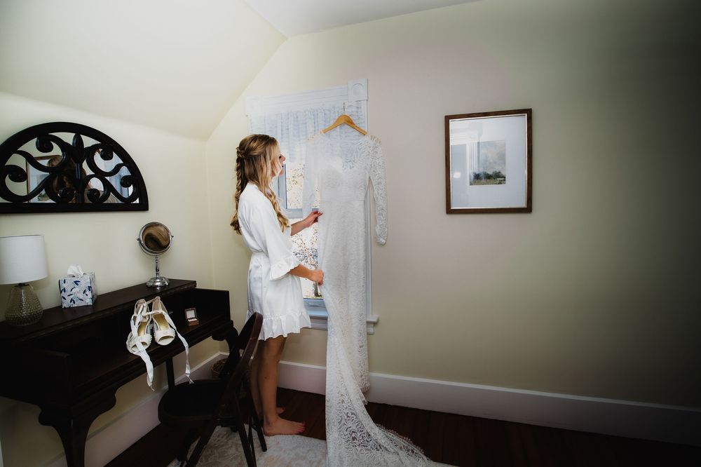 Wedding preparation room with lace dress hanging by window.