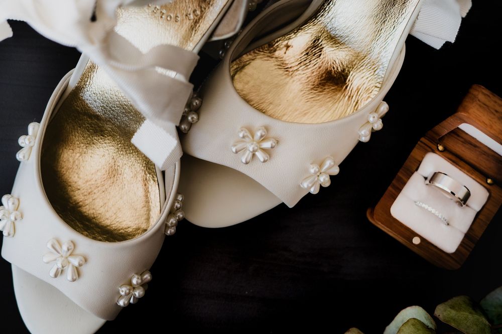 White wedding shoes with delicate lace details arranged on a dark background.