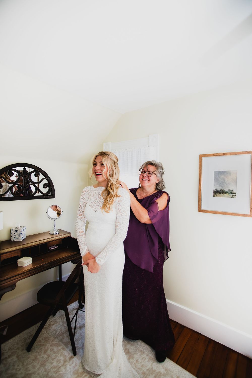 Wedding dress preparation moment in a bright white room with purple accents.