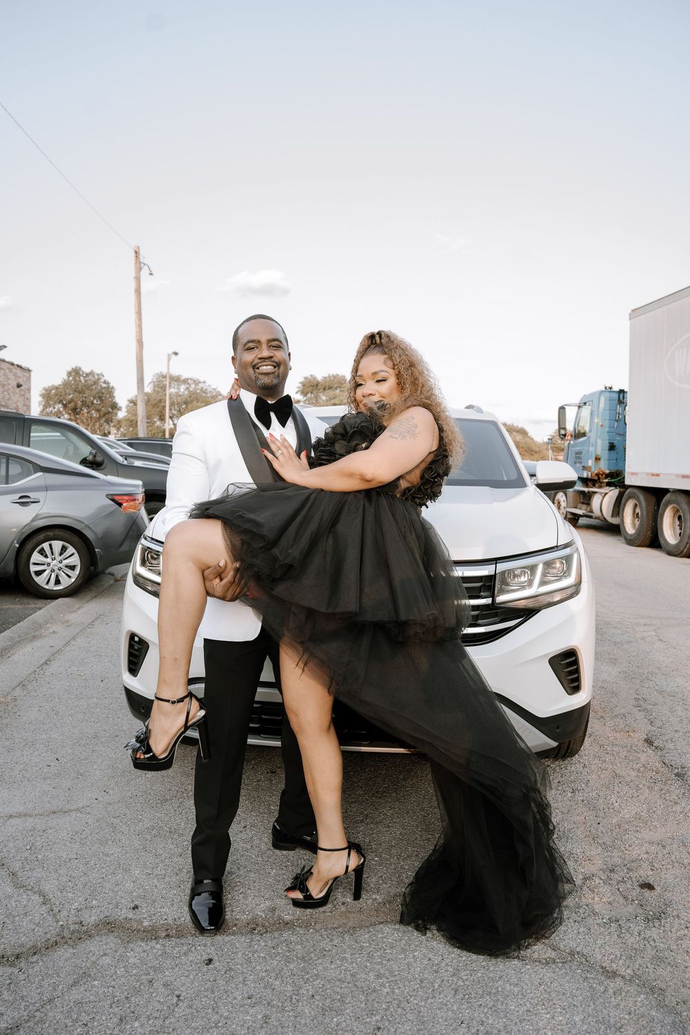 A couple in formal attire poses together near parked cars in a series of romantic outdoor shots.