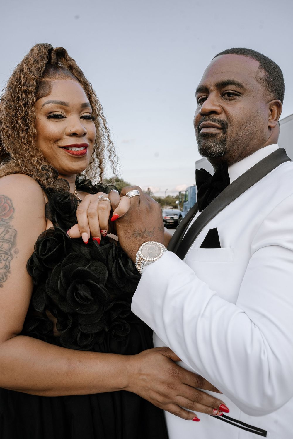 A romantic couple embraces while wearing contrasting black and white formal outfits.