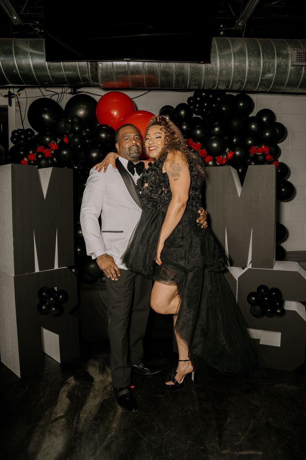 Guests dancing and celebrating at an elegant party with black balloon decorations in the background.