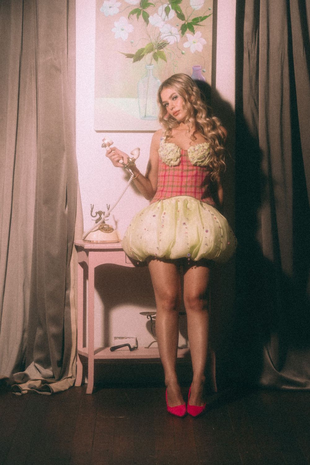 Vintage-inspired scene with bubble dress and rotary phone on pink side table.