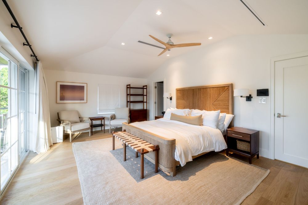 Spacious modern bedroom with hardwood floors, custom headboard, and natural lighting.