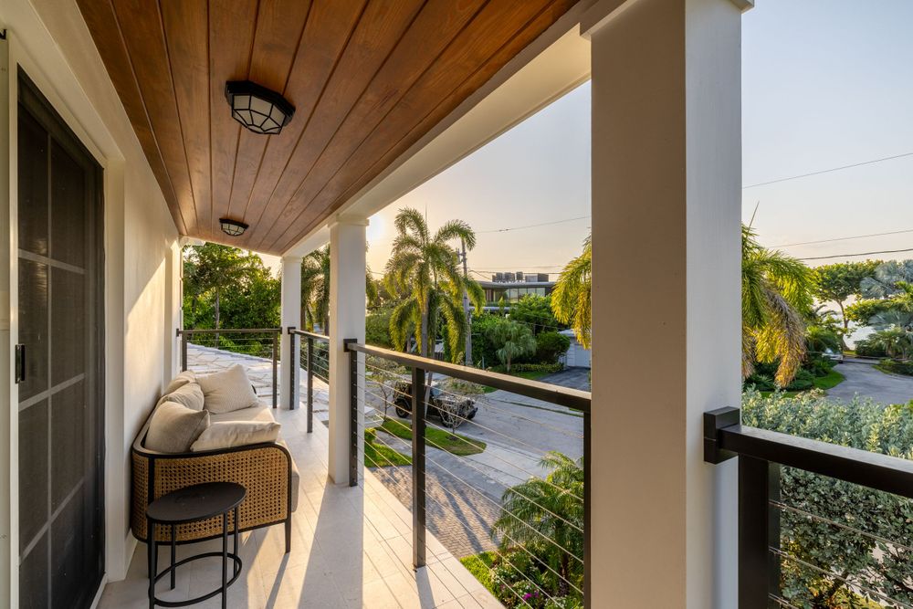 Covered balcony with wooden ceiling and palm tree views in upscale Miami residence.