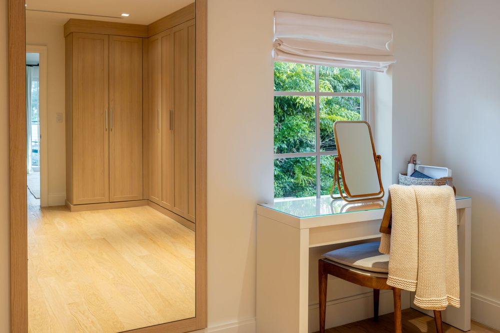 Elegant vanity nook with mirror and wooden cabinetry in bright interior space.