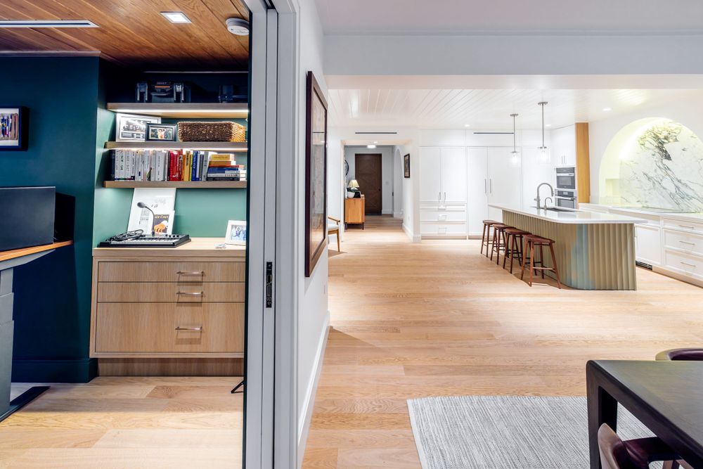 Open concept space with teal accent wall, built-in shelving, and hardwood floors.