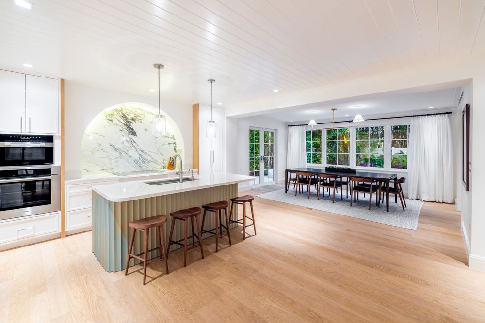 Open concept dining and kitchen area with marble feature wall and light wood flooring.