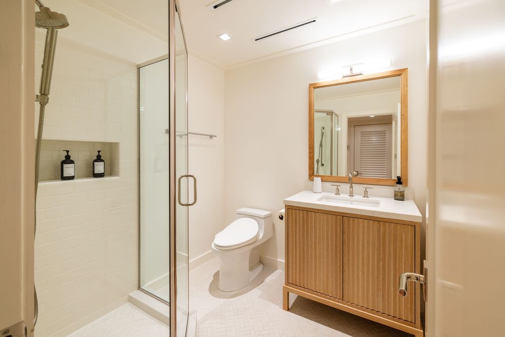 Modern bathroom with glass shower, wooden vanity, and neutral color scheme.