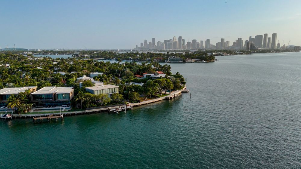 Panoramic aerial shot of Miami's skyline and waterfront mansions along the coast.