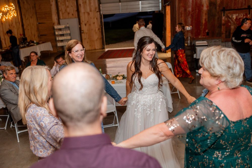 Guests dancing and celebrating together at a rustic barn wedding reception.