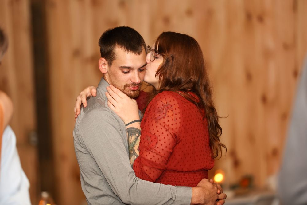 A couple sharing an intimate slow dance together in a rustic wooden venue.