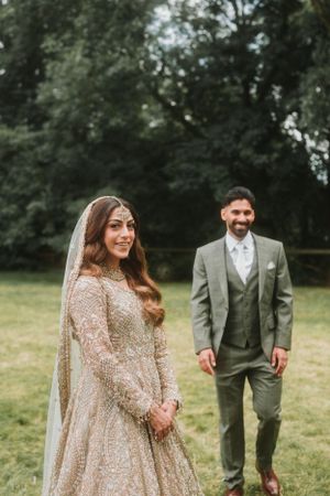 Couple in fusion wedding attire standing in a garden setting.