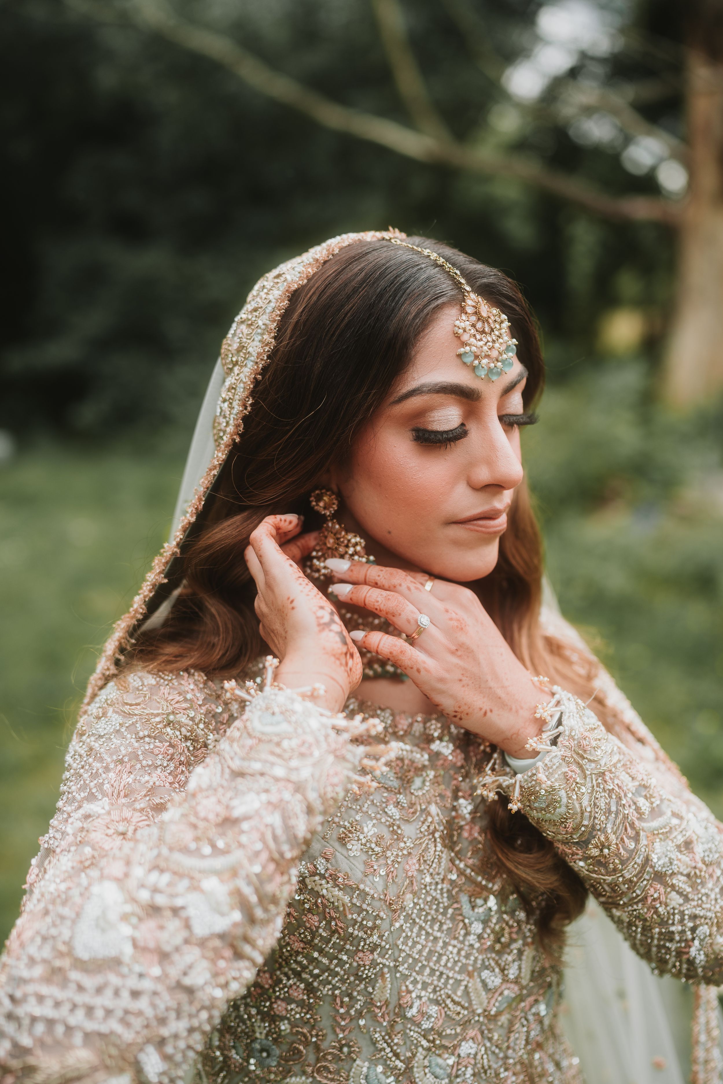 Bridal portrait showcasing intricate Pakistani wedding jewelry and embellished cream dress.