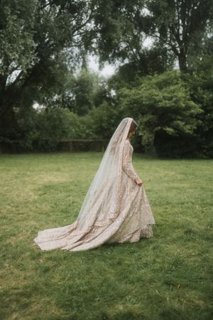 Ethereal bridal portrait showing flowing lace dress and veil against lush garden backdrop.