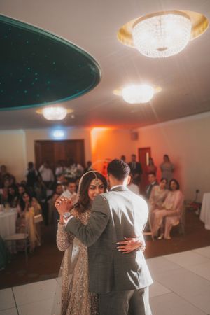 Wedding reception dance scene with decorative ceiling lights and guests watching.
