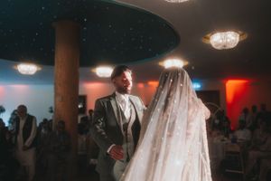 Wedding couple dancing at a reception with teal ceiling and chandeliers.