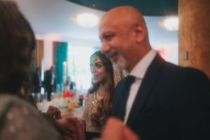 Wedding celebration scene with guests mingling under decorative lighting.