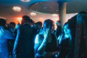 Dance floor crowd at a reception under blue mood lighting.