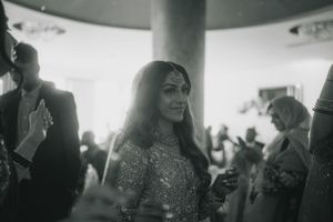 Black and white candid shot of a guest in formal attire at a wedding reception.
